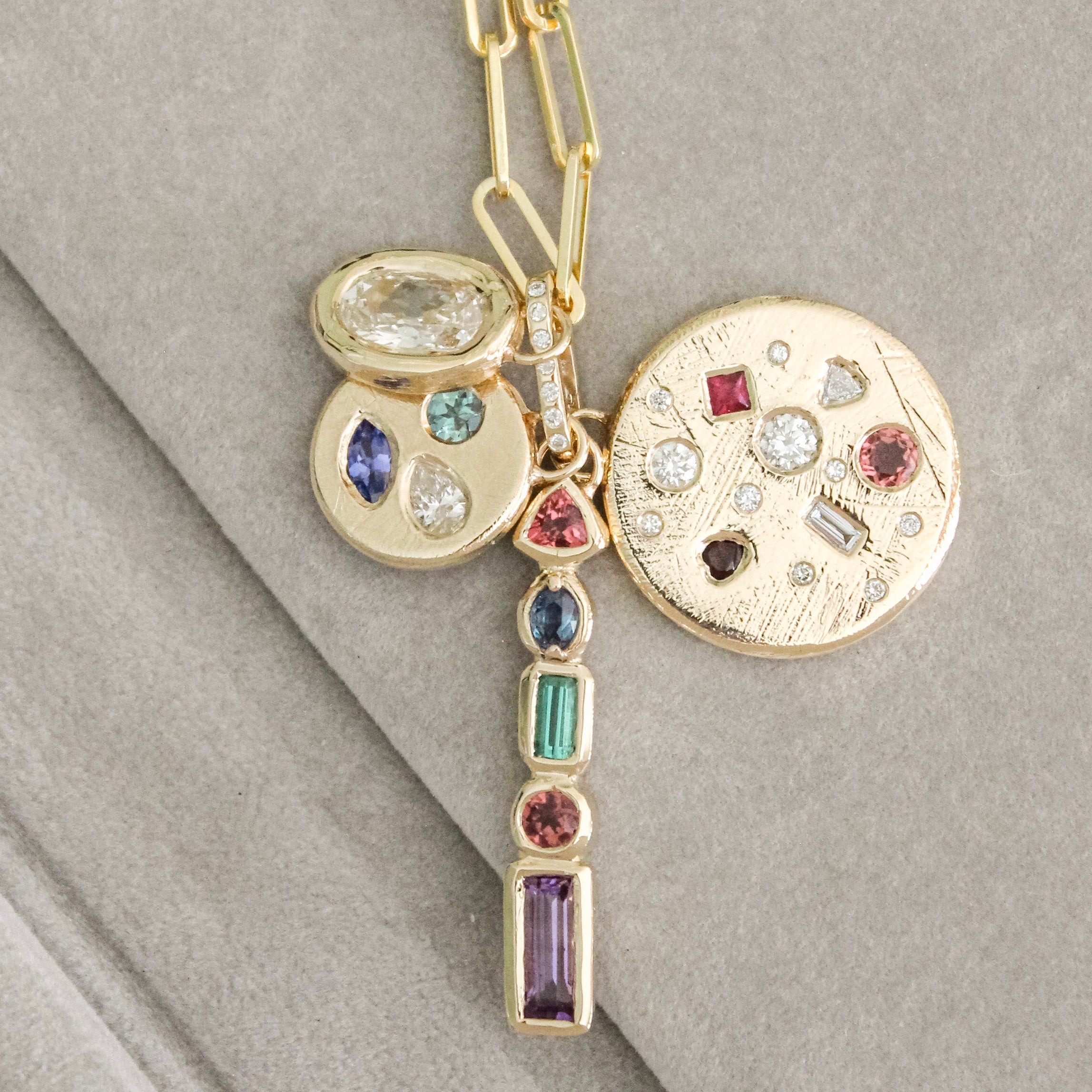 Layered custom gold charms with hand-set gemstones, designed and made by Mary Frances Maker